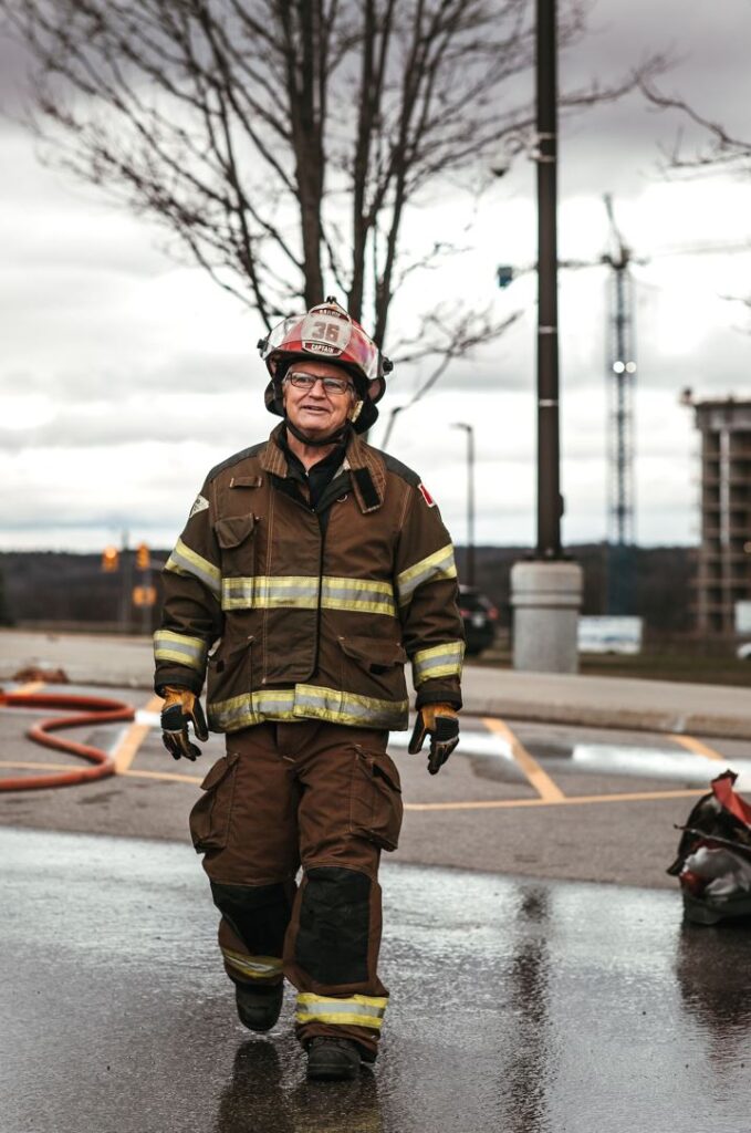 A person wearing a firefighter's uniform walks across a parking lot.