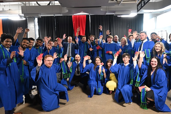 Welcome to Georgian - group of graduating students at convocation dressed in blue gowns cheering and celebrating with President Weaver