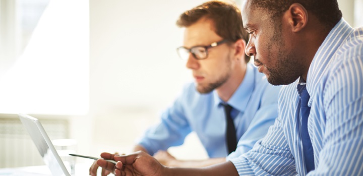 Two businessmen in suits working together on a laptop