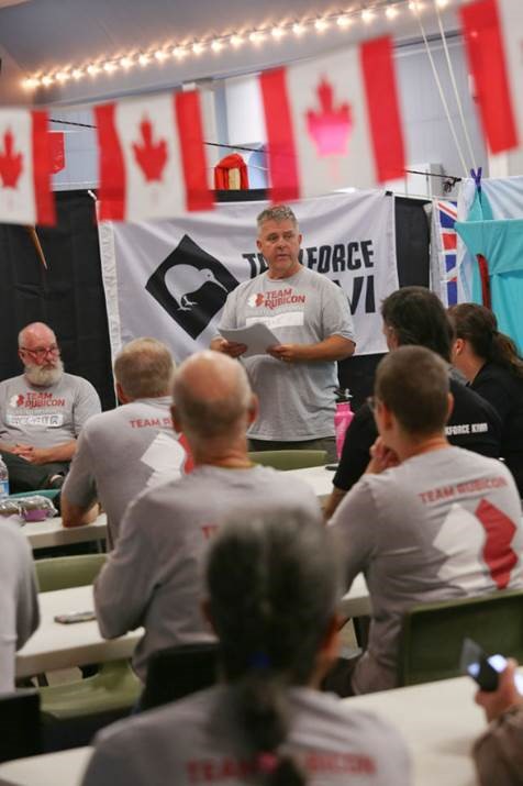 A person stands at the front of a classroom full of people all wearing Team Rubicon T-shirts.