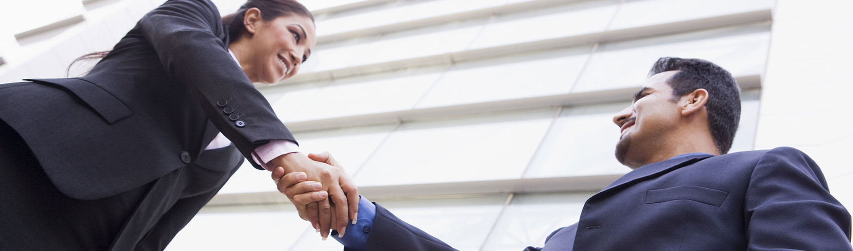 a woman and a man dressed in business attire shaking hands