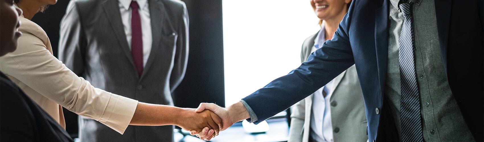a group of men and women dressed in business attire together in a boardroom shaking hands