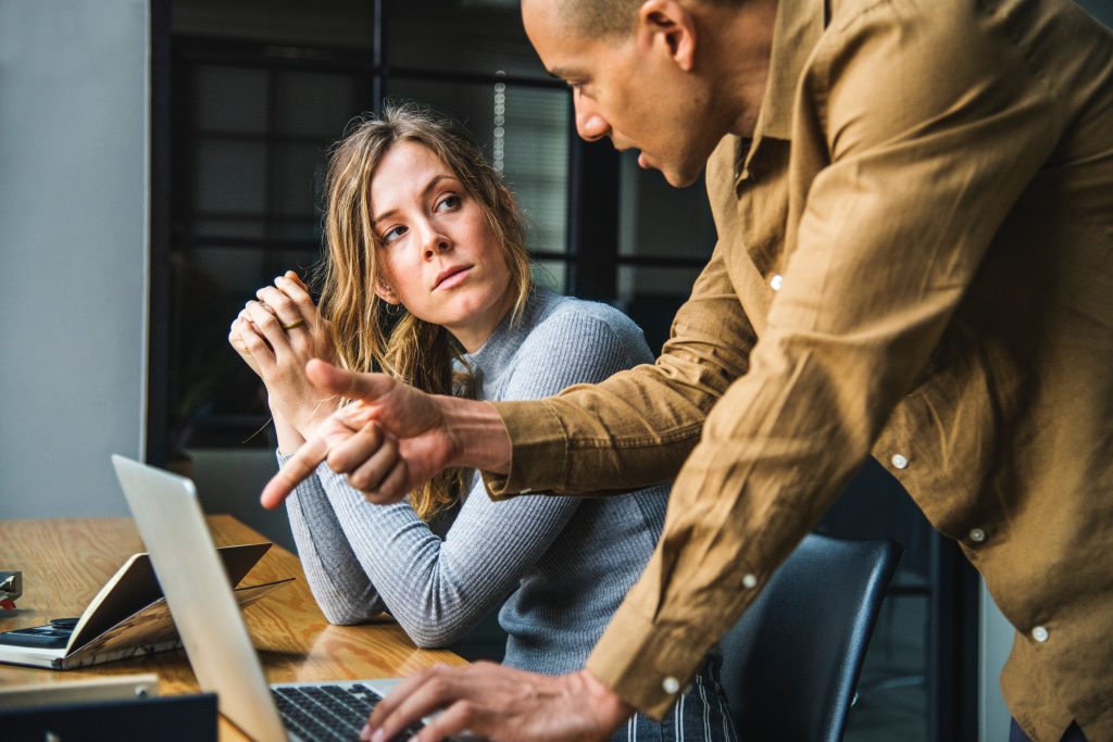 Man explaining something to a young woman on a computer