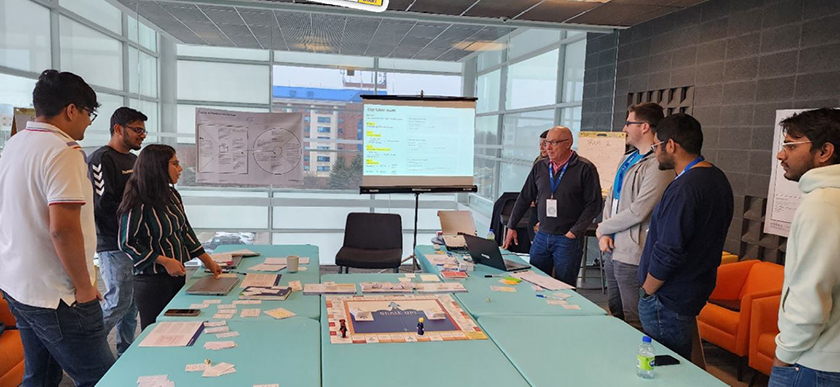 A group of people standing in a room with a large table filled with material