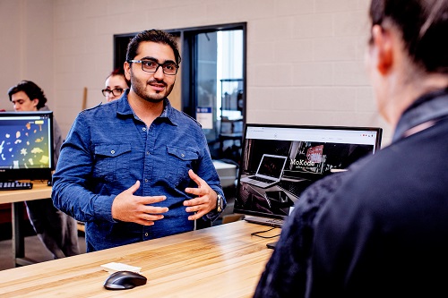 A male student talks to another student about their project at Research, Innovation, Scholarship and Entrepreneurship Day 2018