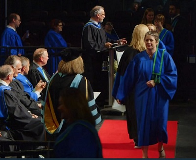 Practical Nursing student and cancer survivor Robyn Haggart walks across stage at convocation in Georgian gown to receive Academic and Career Entrance certificate