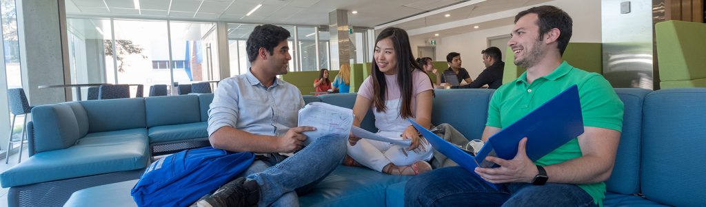 A group of students discussing course work and notes in a student lounge area of the Barrie Campus