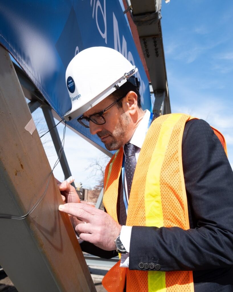 Fabrizio Bozzo, representing Sirco Machinery and the Gene Haas Foundation, signs the bridge — a permanent recognition of the impact of partner and community support on this project.