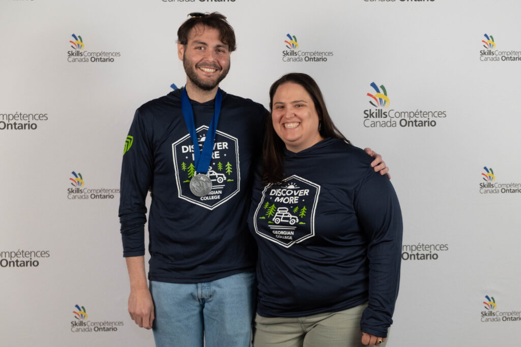 Two people stand together in front of a backdrop reading "Skills Ontario."
