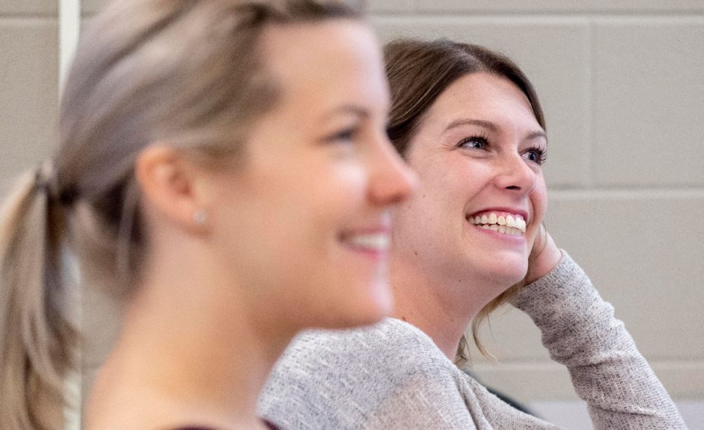two female social service worker students smiling while in class