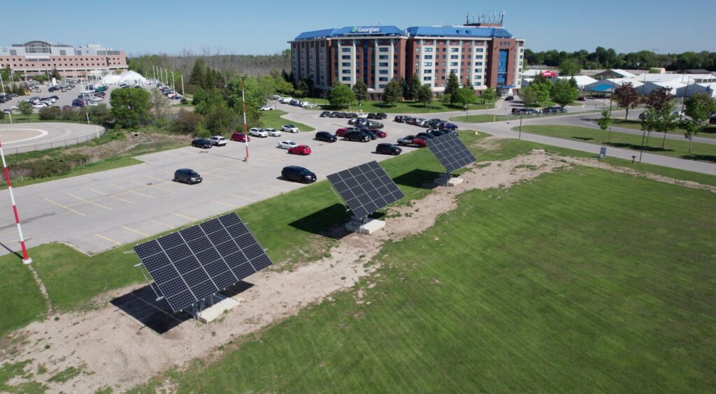 Viewing three black solar panels on green grass from above with a drone.