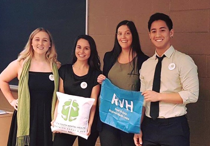 three women and one man holding RVH Foundation signs in front of a classroom blackboard