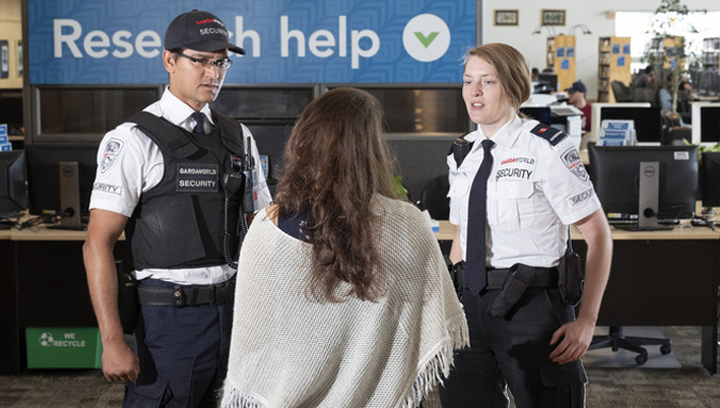 a female student talking to a male and female security guard in the Georgian College Barrie Campus library