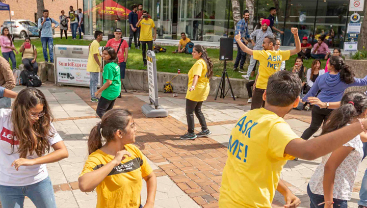 a group of students outside dancing in a circle to music on Orientation day