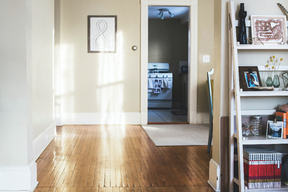 student housing showing beige walls, hardwood floors, a shelf with decorations and a stove with towels hanging