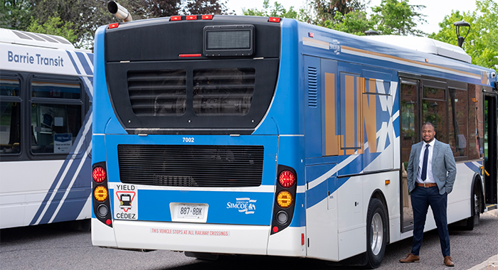 Georgian alumni Ronjay standing in front of Simcoe County Linx and Barrie Transit busses