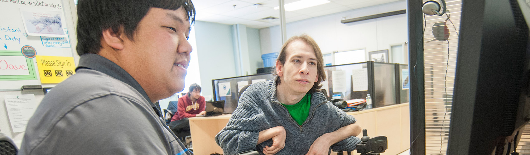an accessibility advisor assisting a student with adaptive technology; both are looking at a computer screen