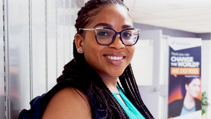 a female student with brown braided hair and glasses smiling
