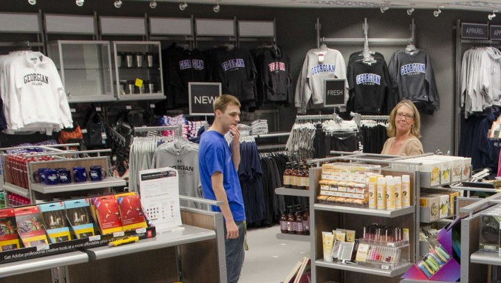 a male and female standing in front of shelves clothing racks inside Georgian Stores