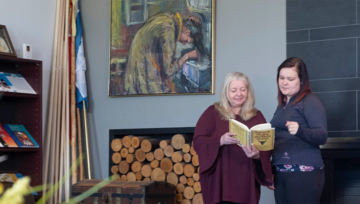 two females reading from a book at the Barrie Campus Indigenous Resource Centre