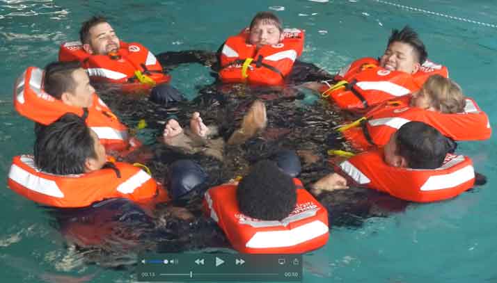 Marine crew conducting marine safety training in lifejackets in a swimming pool
