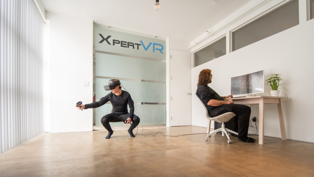 A person in a VR suit in a brightly light office. 