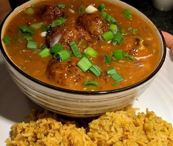 Food in a bowl with rice on a plate next to it.